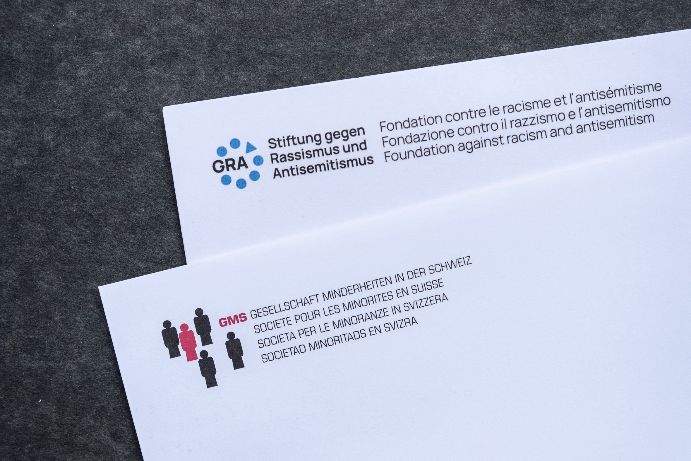 Zwei Briefcouverts, die übereinander liegen und die Logos der GRA und der GMS zeigen.